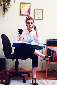 A person sits in a desk chair on the phone