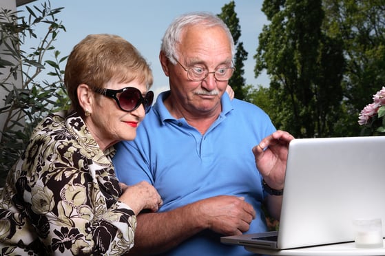 Two older people use a laptop to attend an elearning webinar