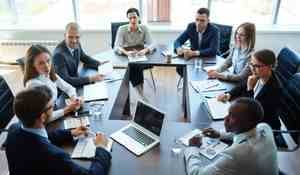 A group of people sit around a table attending a shareholder meeting